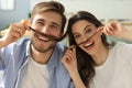 Portrait of cute young playful couple teasing with fake mustache sitting in sofa Royalty Free Stock Photo