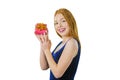 Portrait of a cute young red-haired girl who stands half a turn and holds a small box with a gift near her face, holding Royalty Free Stock Photo