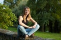 Portrait of the Cute Young Woman Sitting in the Park During Sunset in Jeans and Black Shirt. Royalty Free Stock Photo