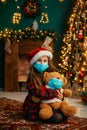 Portrait of cutel little child girl in medical mask playing with Taddy bear, New year holiday concept. Covid-19 concept