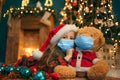 Portrait of cutel little child girl in medical mask playing with Taddy bear, New year holiday concept. Covid-19 concept