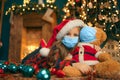 Portrait of cutel little child girl in medical mask playing with Taddy bear, New year holiday concept. Covid-19 concept