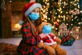 Portrait of cutel little child girl in medical mask playing with Taddy bear, New year holiday concept. Covid-19 concept