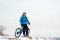 Portrait of Cyclist in Blue Resting with Mountain Bike on Rocky Winter Hill. Extreme Sport and Enduro Biking Concept. Royalty Free Stock Photo