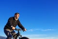 Portrait of cyclist seen from below with blue sky.