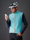 Cyclist wearing helmet and blue windbreaker, looking at smartphone