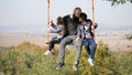 Portrait of dad swinging with daughters on a swing under a tree. Royalty Free Stock Photo