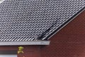 A portrait of a damaged black tile roof of a house. The building got destroyed by a big storm with high wind speeds on the Royalty Free Stock Photo