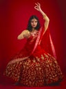 Portrait, dance and Indian woman with fashion, traditional dress and celebration against a red studio background. Face