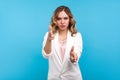 Portrait of dangerous woman pointing finger pistols to camera, threatening with hand gun. isolated on blue background