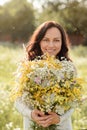 Portrait of a dark-haired girl with a large bouquet of wildflowers