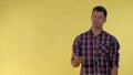 Portrait of dark-haired man in checkered shirt showing negative feelings and giving thumbs down.