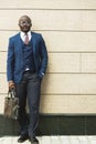 Portrait of dark-skinned african american businessman in suit outdoors posing while standing against background of Royalty Free Stock Photo