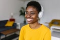 Portrait of daydreaming young african woman listening to music with headphones