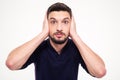 Portrait of dazed bearded young man closed ears by hands Royalty Free Stock Photo