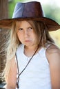 Portrait of deeply offended young girl dressed cowboy leather hat and white shirt, purse lips, injured look