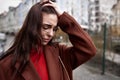 Portrait of deeply upset young woman on the street in a warm coat touching her head in mental paint. depression concept Royalty Free Stock Photo