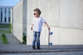 A portrait of defiant boy with skateboard outdoors.