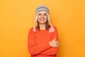 Portrait of delighted confident woman wearing orange sweater and knitted earflap hat, crossed her arms, looking at camera with Royalty Free Stock Photo