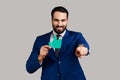 Delighted handsome bearded businessman pointing at camera with smile and showing paper thumb up. Royalty Free Stock Photo