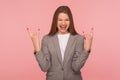 Portrait of delighted overjoyed woman in business suit showing rock and roll hand sign and yelling