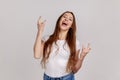 Overjoyed woman showing rock and roll hand sign and yelling, looking crazy with devil gesture. Royalty Free Stock Photo