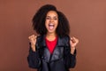 Portrait of delighted pretty carefree girl raise fists scream yes isolated on brown color background Royalty Free Stock Photo