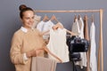 Portrait of delighted satisfied woman designer with bun hairstyle, showing her new collection, using camera with tripod for