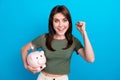 Portrait of delighted successful person hold money bank pig raise fist isolated on blue color background Royalty Free Stock Photo