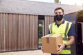 Portrait Of Delivery Driver Wearing Mask Holding Package Outside House Royalty Free Stock Photo