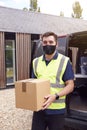 Portrait Of Delivery Driver Wearing Mask Holding Package Outside House Royalty Free Stock Photo