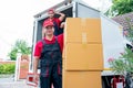 Portrait of delivery man stand near stack of boxes and look at camera with smiling and his co-worker stand in the back on truck Royalty Free Stock Photo