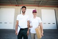 Portrait of delivery man and woman standing with clipboard and parcel