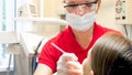 Portrait of female dentist inspecting patients teeth in dentist chair