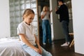 Portrait of depressed cute little daughter sadness looking down sitting on couch during parents quarrelling and fighting Royalty Free Stock Photo