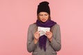 Portrait of depressed flu-sick woman in warm hat and scarf holding tissue, suffering runny nose, sneeze Royalty Free Stock Photo
