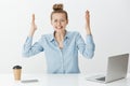 Portrait of depressed upset attractive woman in eyewear, raising palms, clenching teeth and frowning, being under Royalty Free Stock Photo