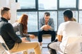 Portrait of depressed young man telling about his mental problem or addiction to other patients sitting in circle. Royalty Free Stock Photo