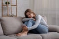 Portrait of depressed young woman sitting on couch with smartphone in her hands Royalty Free Stock Photo