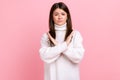 Portrait of determined brunette young woman showing x sign with crossed hands, stop, this is the end