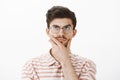 Portrait of determined focused and creative male with funny moustache, rubbing chin, looking up while thinking, making