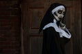 Portrait of scary devilish nun near red brick wall, space for text. Halloween party look