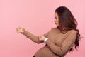 Portrait of diligent purposeful young woman with brunette hair pretending to pull invisible rope, holding something heavy