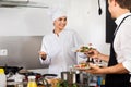 Woman cook giving to waitress ready to serve salad Royalty Free Stock Photo