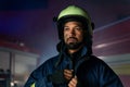 Portrait of dirty firefighter man on duty with fire truck in background at night.