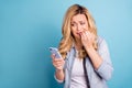 Portrait of disappointed beautiful lady biting her fingers looking at device screen isolated over blue background Royalty Free Stock Photo