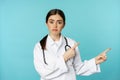 Portrait of disappointed doctor, woman medical worker pointing fingers right and looking sad, regret, gloomy face