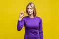 Portrait of disappointed woman showing a little bit gesture. indoor studio shot isolated on yellow background