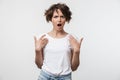 Portrait of disappointed woman with short brown hair in basic t-shirt pointing fingers at herself