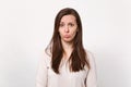 Portrait of disconcerted displeased offended young woman in light clothes blowing lips isolated on white wall background Royalty Free Stock Photo